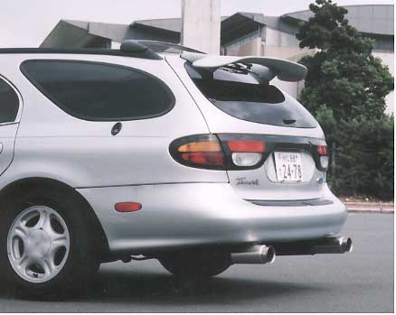 1999 Ford Taurus - Rear three-quarter view of a silver Ford Taurus station wagon fitted with a tall pedestal-mount rear wing, a lower rear valance and dual ch…