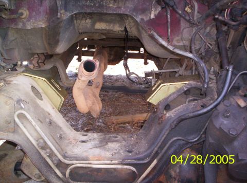 1985 Ford Bronco - The undercarriage of a red vehicle is shown, with visible frame and exhaust system components.