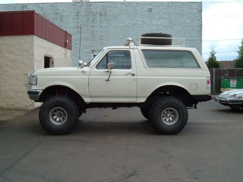 1989 Ford Bronco - This lifted 1989 Ford Bronco features a spare tire mounted on its roof rack and appears to be in good condition.