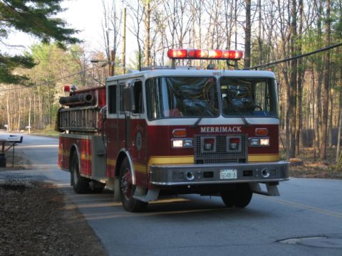 1991 Ford LTD Crown Victoria - A red and white fire truck with emergency lights on top is seen from the front on a paved road.