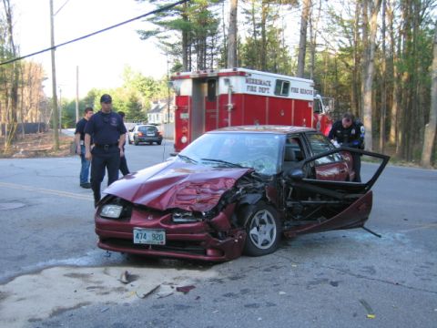 1991 Ford LTD Crown Victoria - A red sedan with significant front-end damage sits on the road next to a fire rescue vehicle, with emergency personnel present.