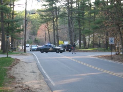 1991 Ford LTD Crown Victoria - A police car with its lights activated is stopped on a road, with other vehicles and a person standing nearby.
