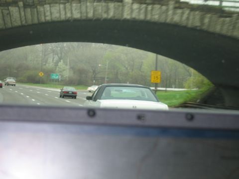 1991 Ford LTD Crown Victoria - A white sedan travels on a highway under a stone bridge, with other vehicles in view.