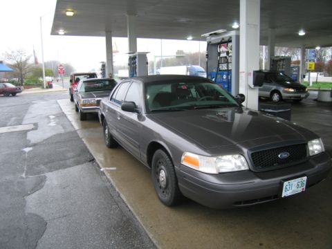 1991 Ford LTD Crown Victoria - A Ford Crown Victoria is parked at a gas station, with other vehicles lined up behind it.