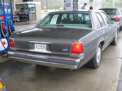 1991 Ford LTD Crown Victoria - A 1991 Ford Crown Victoria LTD is parked at a gas pump, with another car visible behind it.