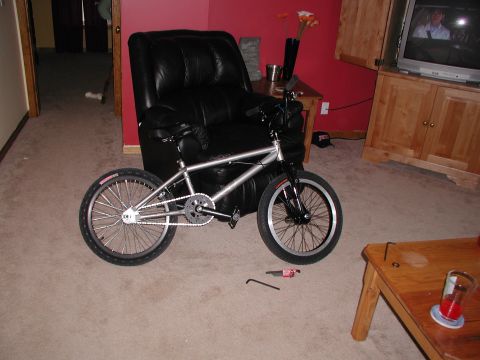 1998 Jeep TJ - A BMX bicycle is positioned indoors, adjacent to a large leather armchair, with a television visible in the background.
