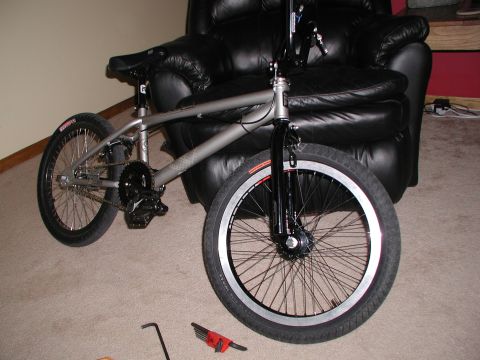 1998 Jeep TJ - BMX bicycle with silver frame and black components, placed next to a leather chair.