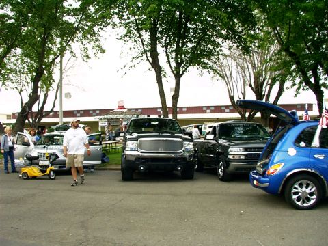 2000 Ford Excursion - Several vehicles are parked outdoors under trees, including a black pickup truck.