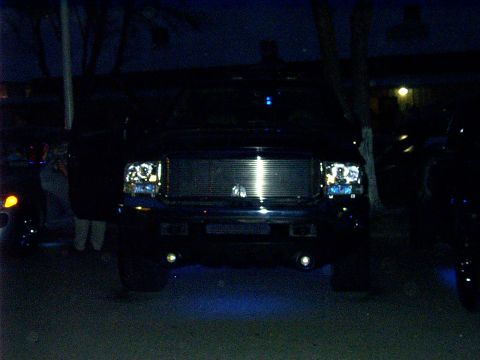 2000 Ford Excursion - Front view of a black 2000 Ford Excursion at night, illuminated by its headlights and blue underglow lighting.
