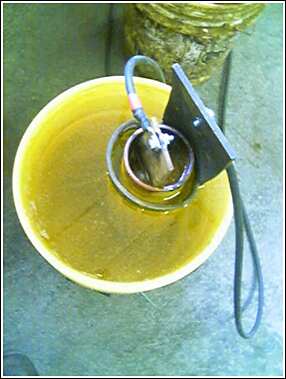 1993 Ford Bronco - A close-up view of a heating element immersed in a bucket of liquid.
