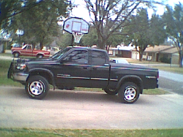 Black Toyota Tundra pickup parked in profile on a driveway in a suburban yard