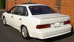 1993 Ford Taurus - The rear of a white 1993 Ford Taurus sedan is visible, parked outdoors.