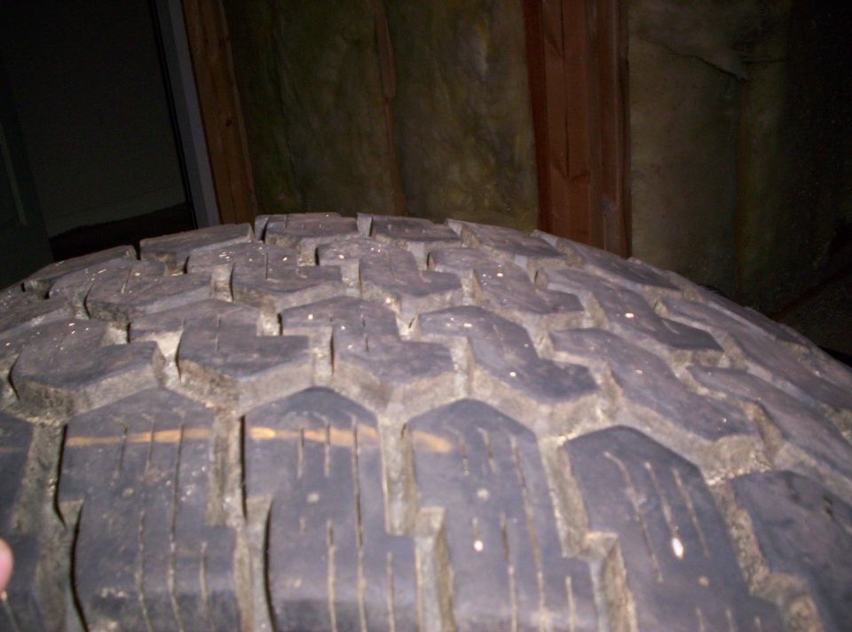 Close-up of an aggressive all-terrain tire tread standing upright indoors