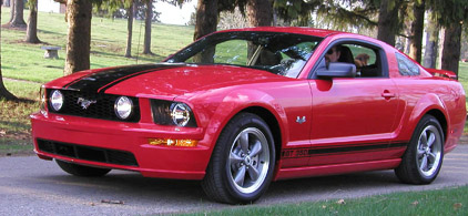 2005 Ford Mustang - Red 2005 Ford Mustang coupe with black racing stripes on hood and side.