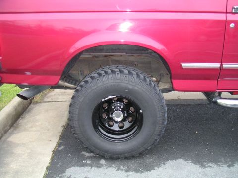 1994 Ford Bronco - Side view of a red 1994 Ford Bronco's rear wheel and fender, fitted with Pro Comp M/T tires.
