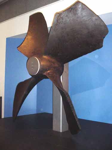 1988 Ford Bronco - A large, four-bladed boat propeller is displayed indoors against a blue wall.