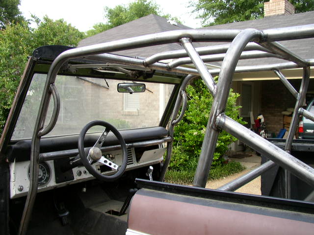 Interior of a Ford Bronco with a custom roll cage, showing the dashboard and steering wheel