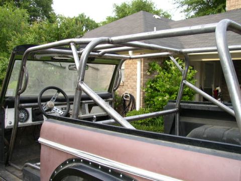 1995 Ford Bronco - Custom metal roll cage installed inside a vehicle, with a view of the steering wheel and dashboard.