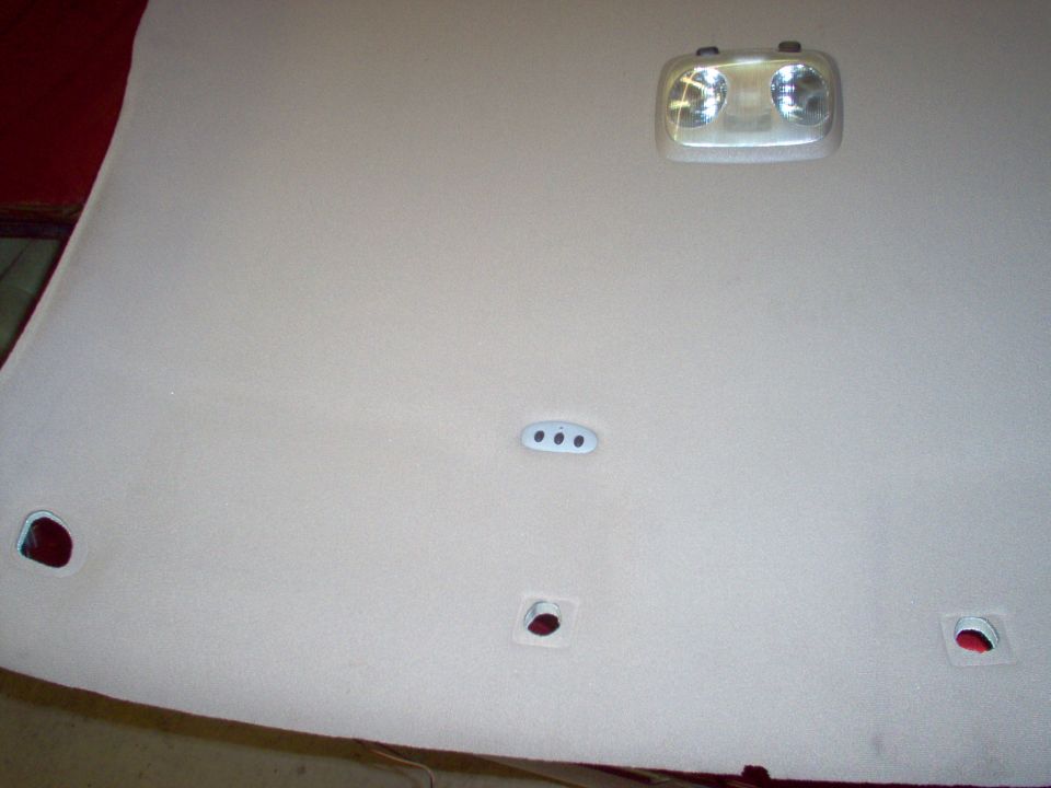 Tan vehicle headliner laid out showing dome light and trim mounting holes