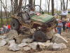 1992 Ford Bronco - An off-road vehicle attempts to traverse a challenging course of large rocks, with spectators gathered in the background.