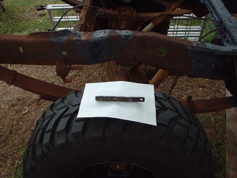 1976 Ford F-150 - A metal part is placed on white paper atop a tire, with rusty vehicle frame in the background.