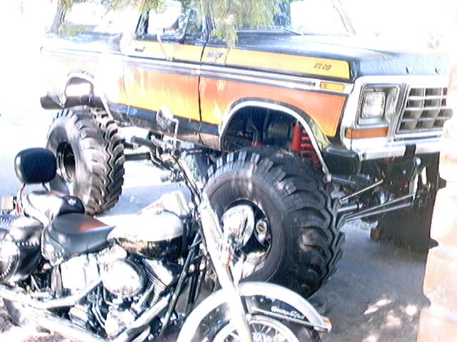 Lifted 1978 Ford Bronco with large tires parked next to a motorcycle