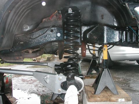 1994 Ford Bronco - Vehicle suspension components, including a coil spring and control arms, are visible while the vehicle is on jack stands.