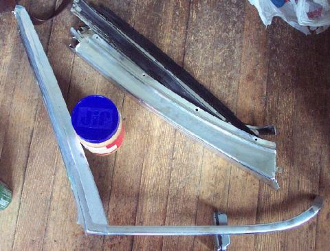 1985 Ford Crown Victoria LTD - Two chrome trim pieces and a jar of something are laid out on a wooden surface.