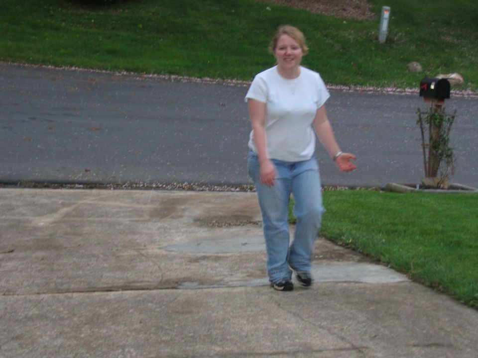 Woman in white t-shirt and jeans walking on a concrete driveway