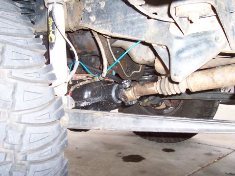 1994 Ford F-150 - Undercarriage view of a vehicle's front axle and suspension system, showing mechanical components and a large tire.
