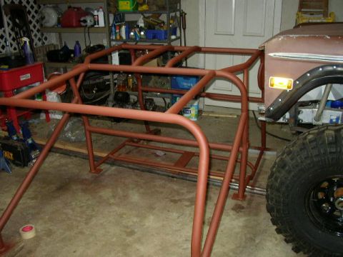 1995 Ford Bronco - A custom roll cage is under construction in a garage setting.