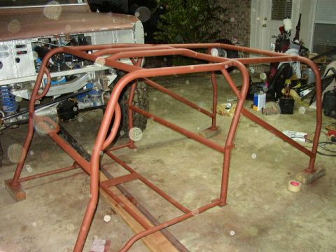 1995 Ford Bronco - A 1995 Ford Bronco is partially visible behind a custom red roll cage, suggesting modifications for off-road use.