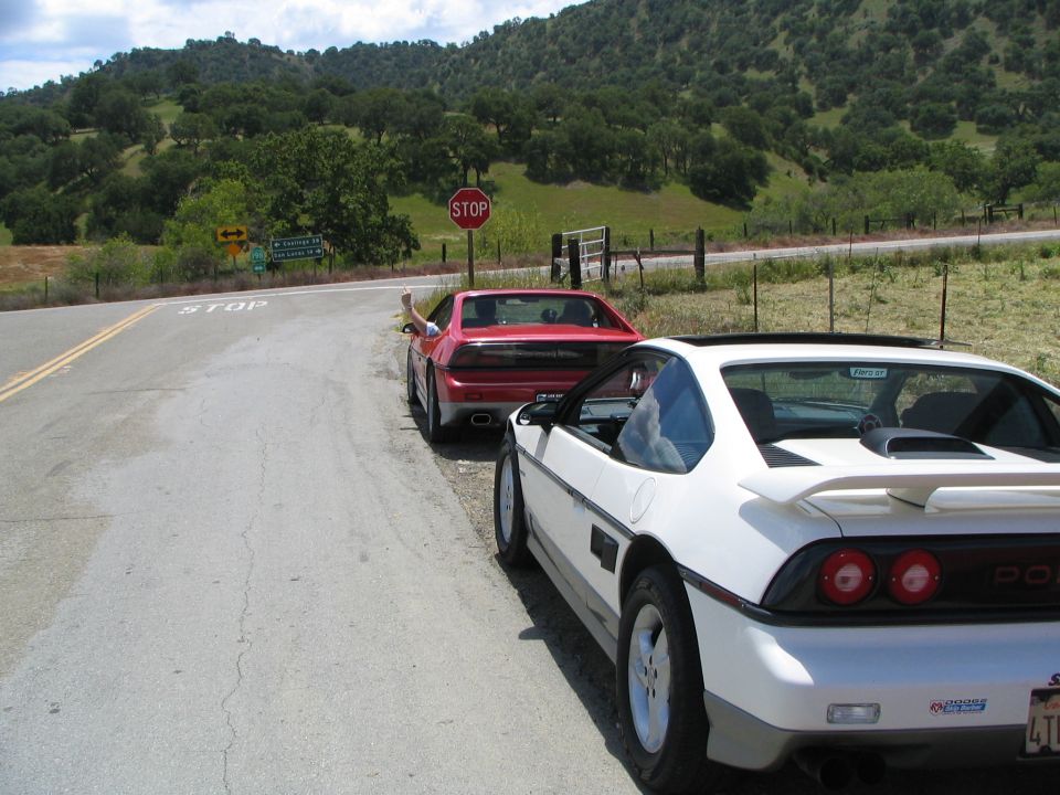 White 1984 Pontiac Fiero parked on a rural road, rear 3/4 view