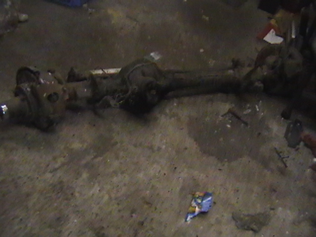 Rusty rear axle assembly on concrete floor