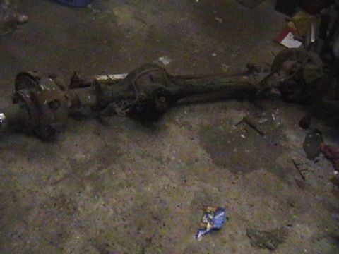 1986 Ford Bronco - A front axle assembly rests on a concrete floor, appearing to be a spare part.