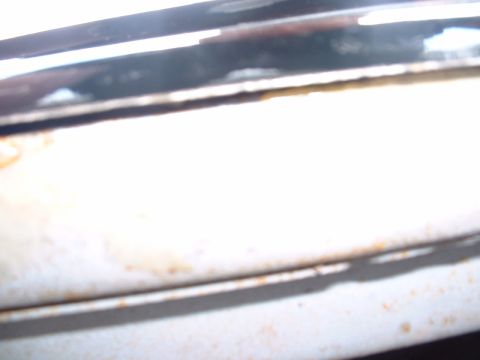 1978 Ford Mustang II - A close-up view of a vehicle's chrome trim and body panel, showing signs of wear and a website watermark.