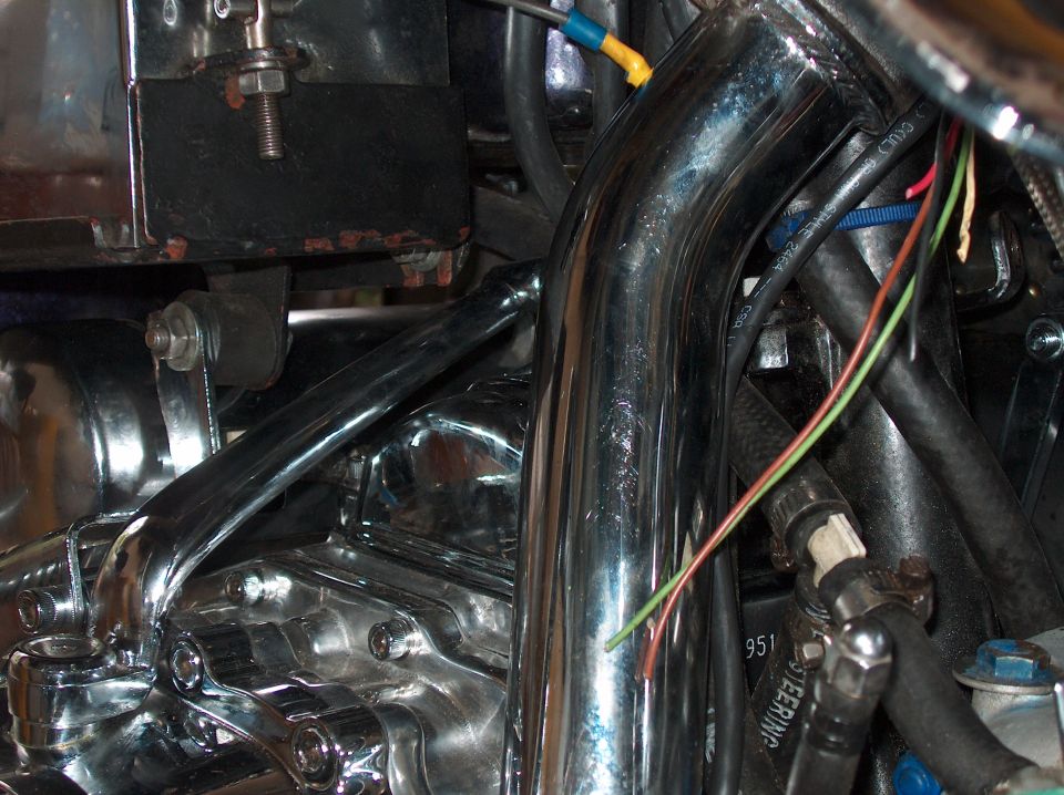 Close-up of chrome exhaust pipes and engine components on a motorcycle, with visible wiring