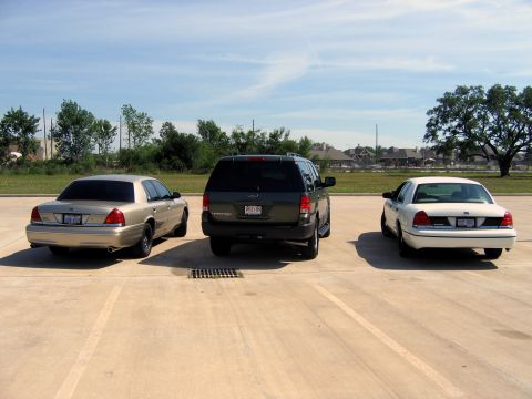 2000 Ford Crown Victoria - Two Ford Crown Victorias and a Ford Expedition parked in a lot under a blue sky.