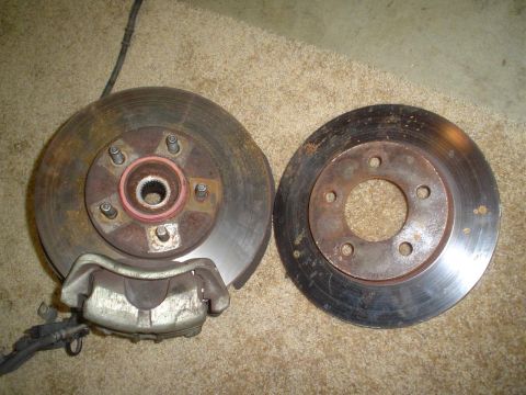 1993 Ford Taurus - Front brake rotor and caliper assembly next to a separate rear brake rotor.