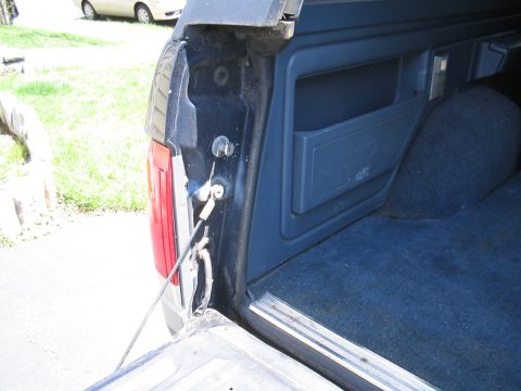 1979 Ford Bronco - The rear cargo area of a dark blue SUV features blue carpeting and built-in storage compartments.