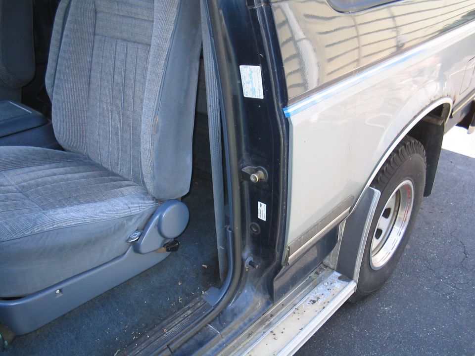 Driver's seat and door jamb of a Ford Bronco. The door is open, showing the interior seat and the exterior side panel and wheel