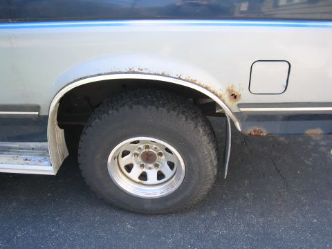 1979 Ford Bronco - This Ford Bronco shows significant rust around the rear wheel well and fuel door, indicating a model year likely in the late 1980s.