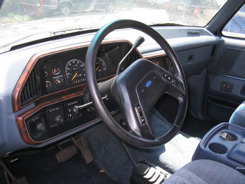 1979 Ford Bronco - Interior view of a Ford truck dashboard, wood grain accents and a prominent steering wheel.