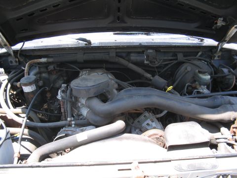1979 Ford Bronco - The engine compartment of a vehicle is shown with various mechanical parts and hoses.