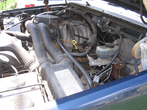 1979 Ford Bronco - The engine bay of a blue vehicle is shown, with various components and hoses visible.
