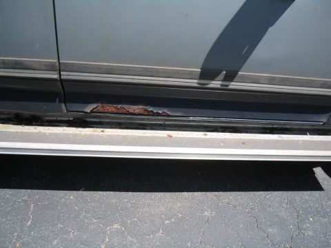 1979 Ford Bronco - The lower body panel of a vehicle displays significant rust damage.