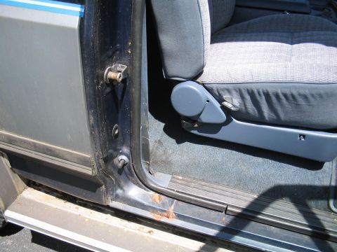 1979 Ford Bronco - Close-up view of the interior door frame and seat of a 1989 Ford Bronco, showing signs of wear and rust.