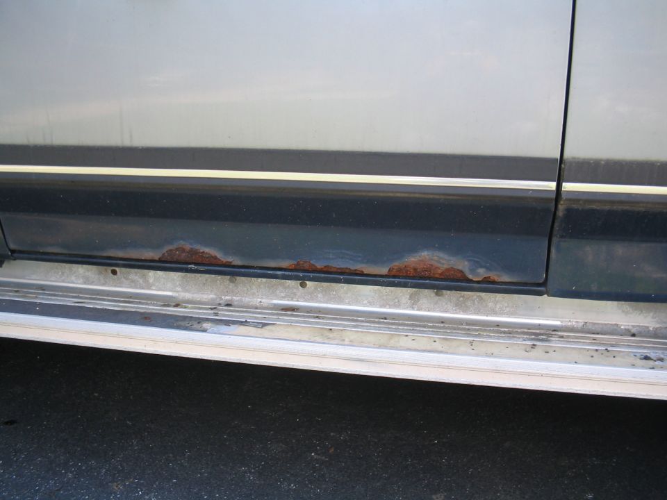 close-up of rust on lower body panel and trim of a vehicle