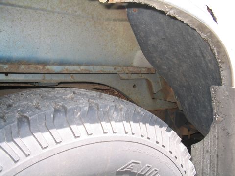 1979 Ford Bronco - Visible rust on the frame and wheel well of a vehicle, with a tire in the foreground.