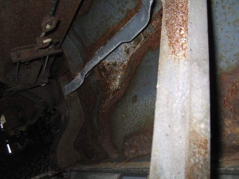 1979 Ford Bronco - The underside of a vehicle displays significant rust damage and visible mechanical parts.